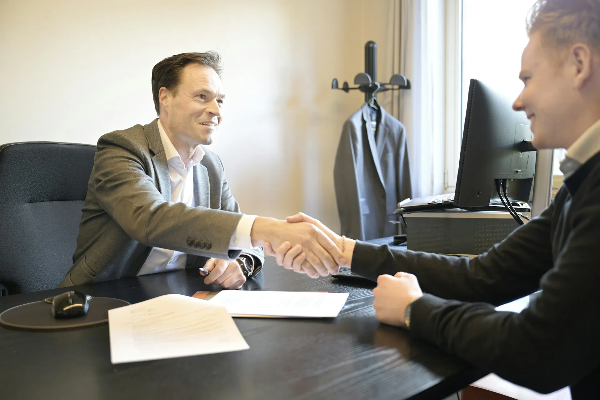 Two business people shaking hands across a desk