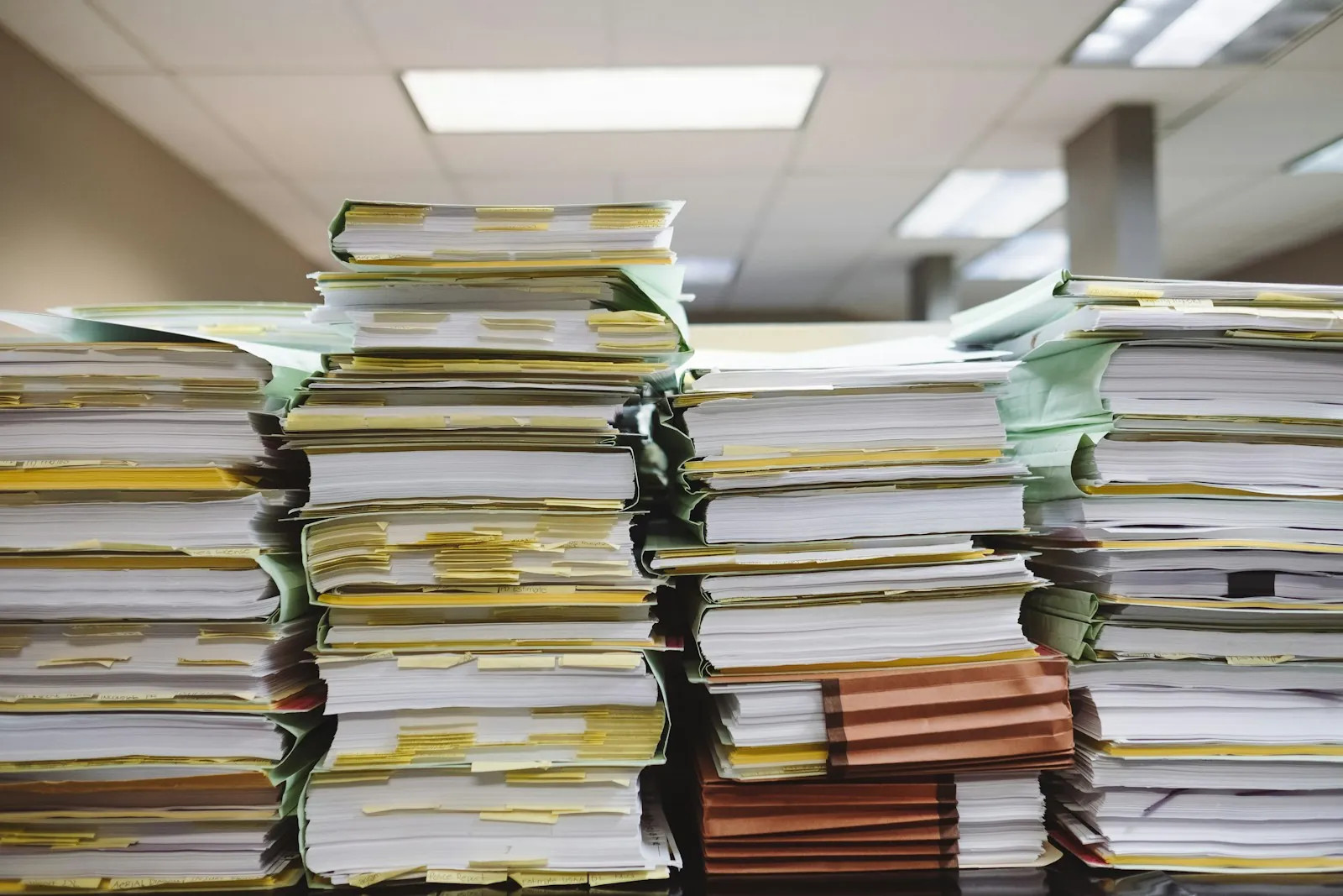 Stacks of paper files on an office desk