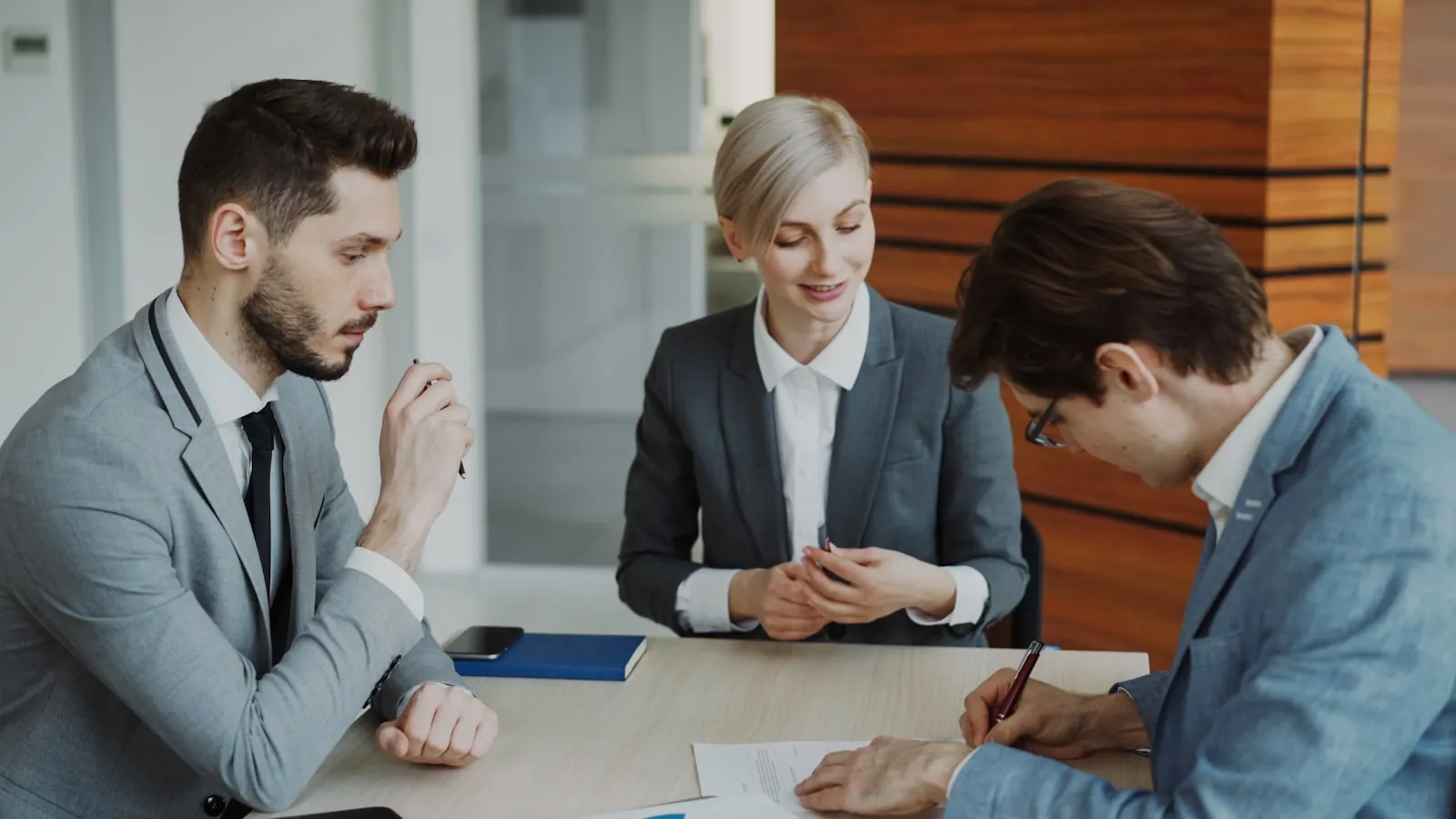 Three attorneys reviewing documents together at a conference table